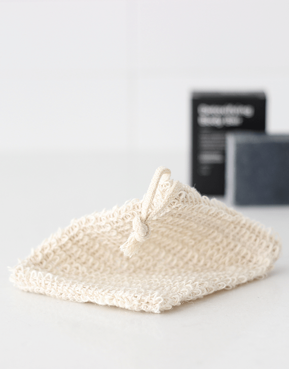 Brown and Coconut Exfoliating Soap Bag with bar of black soap in the background