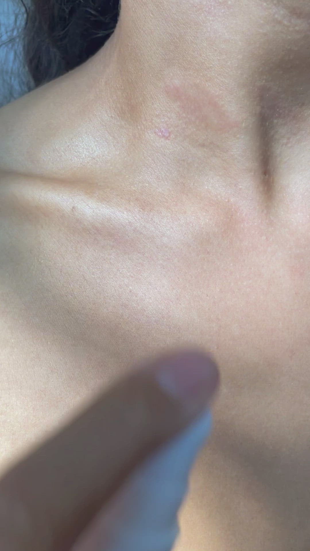 Slow motion and close up video of a hand applying Brown and Coconut Hydrating Face Oil to décolletage