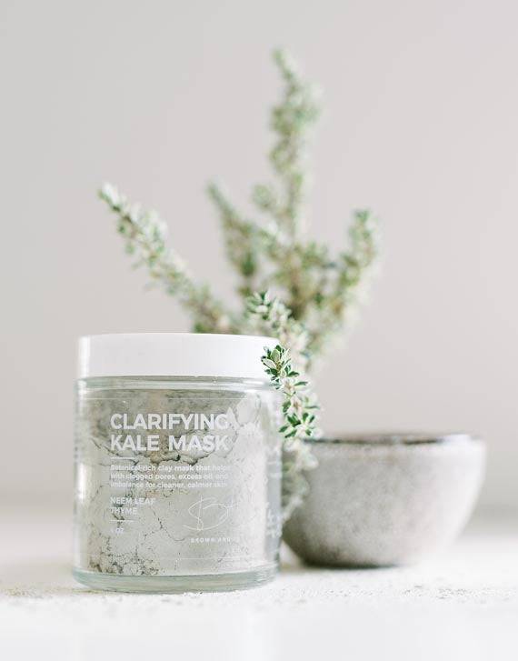 Brown and Coconut Clarifying Kale Mask next to green plant leaves and mini bowl