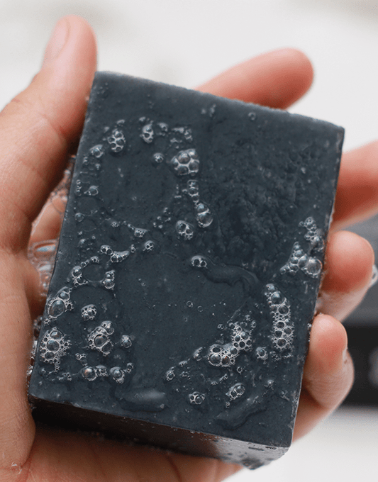 Soapy Brown and Coconut Deep Cleansing Charcoal Soap being held by hand
